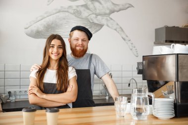 Kahve iş kavramı - pozitif genç sakallı dostum ve güzel çekici Bayan barista çift birlikte modern kahve dükkanında çalışmaktan hoşlanıyor