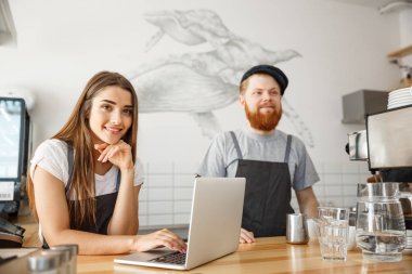 Kahve iş kavramı - neşeli baristas modern kafede online sipariş için onların laptop bakarak.