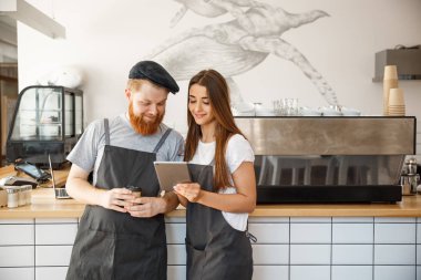 Kahve iş kavramı - online sipariş için onların tablet bakarak neşeli baristas. 