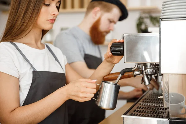 Coffee Business Concept - retrato de la señora barista en delantal preparando y humeante leche para el pedido de café con su pareja mientras está de pie en la cafetería . —  Fotos de Stock