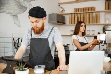 Kahve iş kavramı - sakallı yakışıklı genç barmen, barista veya sipariş dijital tablet menüsünde modern kahve dükkanında konuk ilanıyla Yöneticisi.