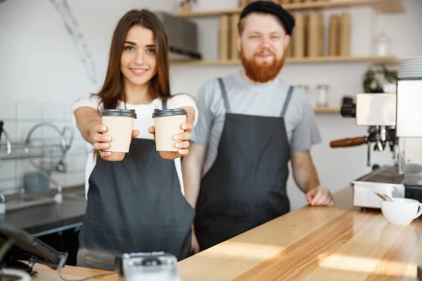 コーヒー ビジネス コンセプト - 肯定的な若いアゴヒゲと美しい魅力的な女性バリスタのカップルを与えることがカスタマーのモダンなコーヒー ショップでコーヒーを奪う — ストック写真