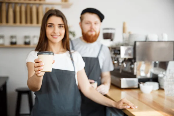 Café Business Concept - joven barbudo positivo y hermosa pareja atractiva barista dama regalando tomar una taza de café para custome en la cafetería moderna —  Fotos de Stock