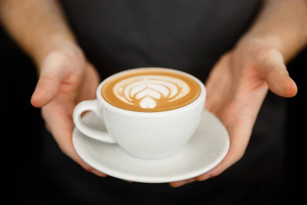 Koncepcja biznesowa Kawa - wyrósł Zamknij kobiece porcję kawy latte art stojąc w kawiarni. Skupić się na kobiece dłonie wprowadzania filiżankę kawy. — Zdjęcie stockowe