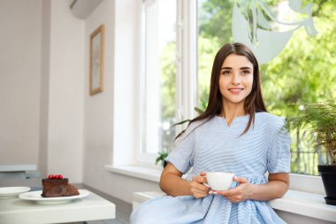 Genç güzel beyaz Bayan zevk içme ve tatlı modern kahve dükkanında öğlen sahip..