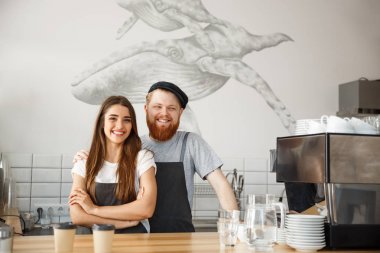 Kahve iş kavramı - pozitif genç sakallı dostum ve güzel çekici Bayan barista çift birlikte modern kahve dükkanında çalışmaktan hoşlanıyor
