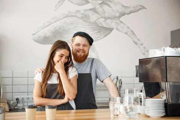 Kávé üzleti koncepció - pozitív fiatal szakállas ember és szép vonzó hölgy barista pár élvezni dolgozik együtt a modern kávézó — Stock Fotó