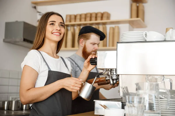 Coffee Business Concept - retrato de la señora barista en delantal preparando y humeante leche para el pedido de café con su pareja mientras está de pie en la cafetería . —  Fotos de Stock