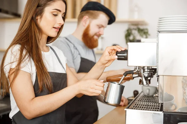 コーヒー ビジネス コンセプト - エプロンの準備とカフェでコーヒー順序立っている間彼女のパートナーのためのミルクを蒸して女性バリスタの肖像画. — ストック写真