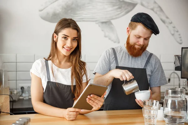 Conceito de negócio de café - felizes jovens empresários casal de pequena loja de café trabalhando e aplainando em tablet . — Fotografia de Stock