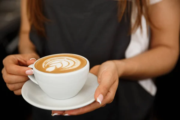 Koncepcja biznesowa Kawa - wyrósł Zamknij kobiece porcję kawy latte art stojąc w kawiarni. Skupić się na kobiece dłonie wprowadzania filiżankę kawy. — Zdjęcie stockowe