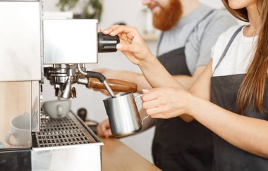 Kahve iş kavramı - Bayan barista hazırlama ve eşi dururken siparişle kahve için süt kafede Buhar önlük portresi.