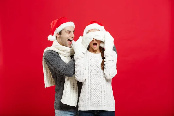 圣诞节概念-一个浪漫的年轻男友的肖像令人惊讶的女朋友在红色演播室背景. — 图库照片