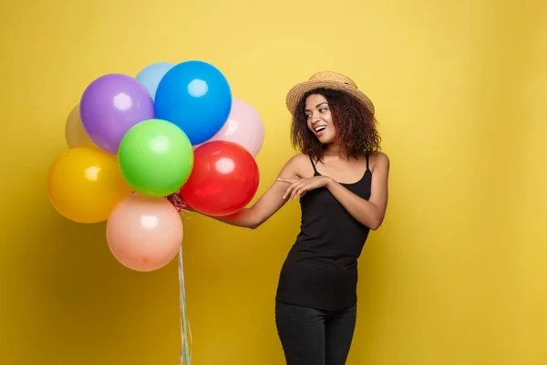 Celebration Concept - Close up Ritratto felice giovane bella donna africana in t-shirt nera sorridente con palloncino partito colorato. giallo pastello studio sfondo — Foto Stock