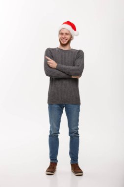 Holiday Concept - Süveter giyen genç sakallı adam oynamaktan ve kopyasal alanla parmak göstermekten zevk alıyor.