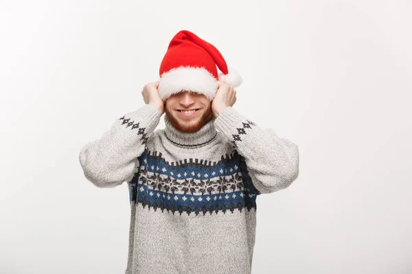 Urlaubskonzept - Junger Bartträger im Pullover spielt gern mit Weihnachtsmütze. — Stockfoto