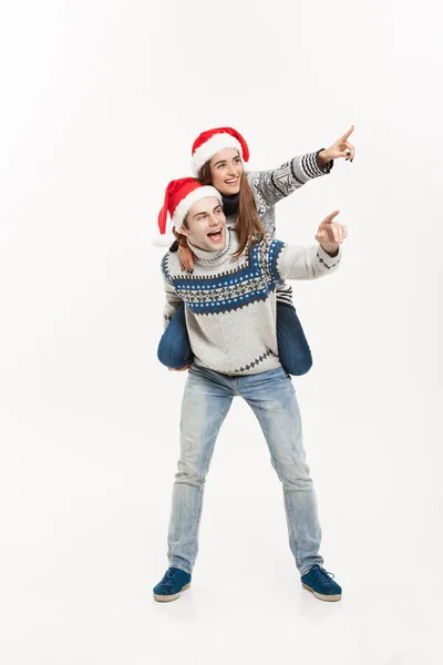 Conceito de Natal - Full-length Jovem casal feliz em camisolas desfrutando de passeio de piggyback isolado no fundo cinza branco — Fotografia de Stock