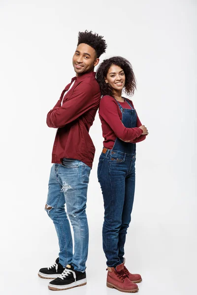 Cheerful African American man and woman with crossed hands standing back to back over isolated white background. — Stock Photo, Image