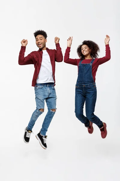 Estilo de vida, felicidad y concepto de personas: Feliz joven encantadora pareja afroamericana saltando sobre fondo gris brillante . —  Fotos de Stock