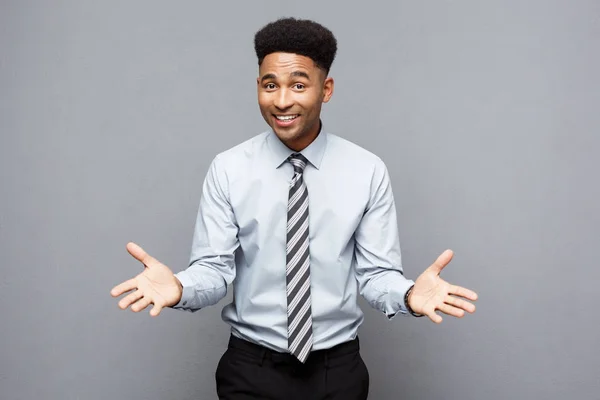 Business Concept - Joven joven afroamericano confiado mostrando las manos frente a él con una expresión sorprendente sobre un fondo gris . —  Fotos de Stock