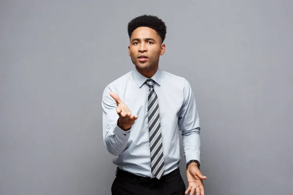 Affärsidé - säker glada unga afroamerikanska visar händerna framför honom med besviken uttryck över grå bakgrund. — Stockfoto
