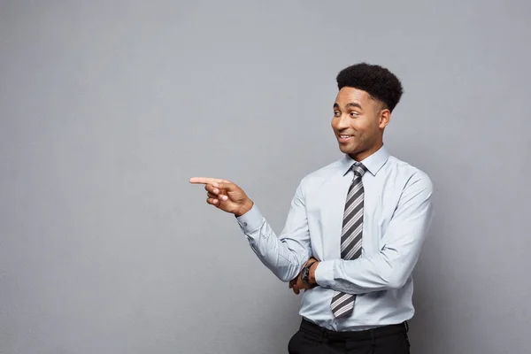 Geschäftskonzept - selbstbewusster, nachdenklicher junger Afroamerikaner zeigt mit dem Finger auf grauen Hintergrund. — Stockfoto