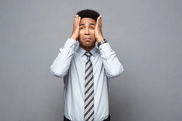 Business concept - portrait of frustrated stressed African American business man on grey background.