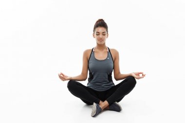 Sağlıklı ve Fitness kavramı - güzel Amerikan Afrika Bayan fitness giyim yoga ve meditasyon yapıyor. Beyaz arka plan üzerinde izole.