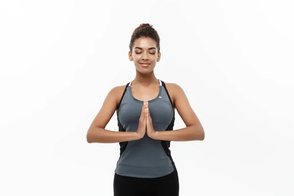 Nyttigt och Fitness koncept - vackra amerikanska afrikanska damen i fitness kläder gör yoga och meditation. Isolerad på vit bakgrund. — Stockfoto