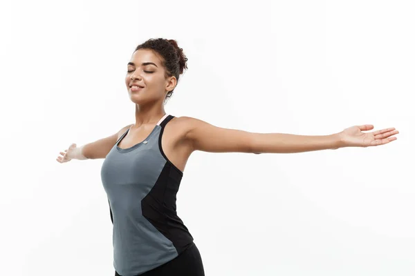 Nyttigt och Fitness koncept - porträtt av unga vackra African American med henne händer utsträckta och avslutande ögon känsla koppla av. Isolerad på vita studio bakgrund. — Stockfoto