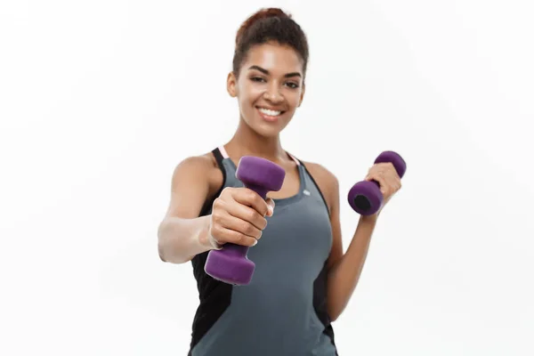 Healthy and Fitness concept - Beautiful American African lady in fitness clothes workout with dumbbell. Isolated on white background. — Stock Photo, Image