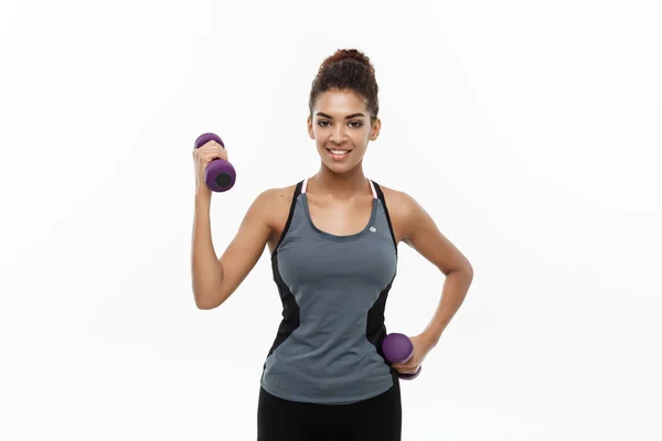 Healthy and Fitness concept - Mooie Amerikaanse Afrikaanse dame in fitness kleding workout met halter. Geïsoleerd op witte achtergrond. — Stockfoto
