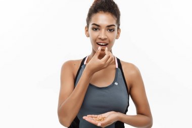 Sağlıklı ve Fitness kavramı - güzel Afrikalı-Amerikalı balık yağı hapı aldığın Closeup portresi. Beyaz stüdyo arka plan üzerinde izole.