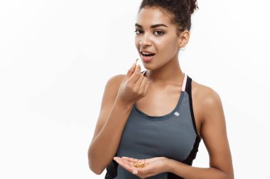 Sağlıklı ve Fitness kavramı - güzel Afrikalı-Amerikalı balık yağı hapı aldığın Closeup portresi. Beyaz stüdyo arka plan üzerinde izole.