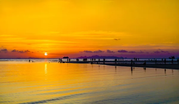 Belo pôr do sol dramático com pessoas na praia . — Fotografia de Stock