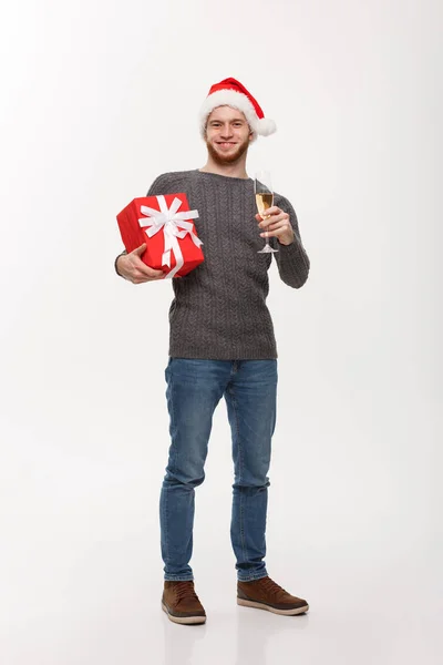 Weihnachtskonzept - glücklicher junger Mann mit Bart hält Geschenk in der Hand und Champagner feiert Weihnachten isoliert auf weißem Hintergrund. — Stockfoto