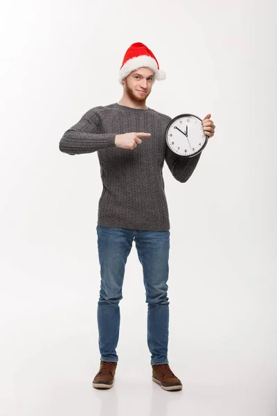 Conceito de férias - Homem barba bonito jovem apontando no relógio branco dizendo as horas — Fotografia de Stock