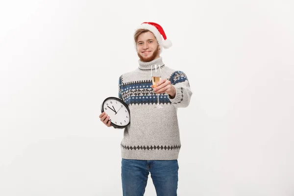 Urlaubskonzept - junger gutaussehender Bartträger im Pullover mit weißer Uhr und Champagner über weißem Studiohintergrund. — Stockfoto