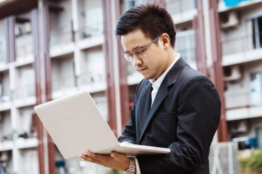 Kavram iş - yakışıklı Asya iş adamı gayrimenkul yatırım dizüstü bilgisayar ile çalışma