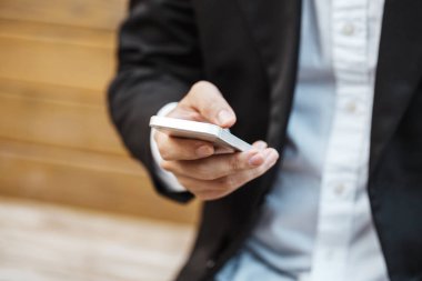 Modern siyah takım elbise ve beyaz gömlek, mesaj mobil akıllı telefon giyen yakın çekim akıllı iş adamı.