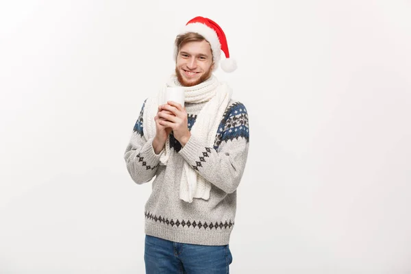 Conceito de Natal - Homem barba jovem em suéter e chapéu de santa segurando uma xícara de café quente isolado em branco com espaço de cópia . — Fotografia de Stock