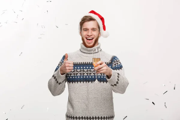 Chirstmas concept - fröhlicher junger kaukasischer Bartträger mit Champagnerglas mit Konfetti-Hintergrund, der Weihnachten feiert. — Stockfoto