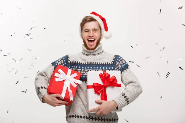 Chirstmas Concept - Happy νεαρό Καυκάσιος γενειάδα άνθρωπος που κρατά το παρόν πλαίσιο με φόντο κομφετί τον εορτασμό για την ημέρα των Χριστουγέννων. — Φωτογραφία Αρχείου