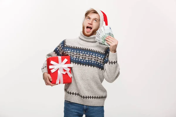 Διακοπές Concept - άνθρωπος νέος γένια, κρατώντας ένα χριστουγεννιάτικο δώρο πλαίσιο και τα χρήματα πάνω από το λευκό φόντο — Φωτογραφία Αρχείου