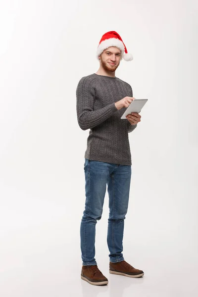 Tatil kavramı - Genç sakallı yakışıklı adam beyaz arka plan üzerinde dijital tablet üzerinde çalışıyor. — Stok fotoğraf