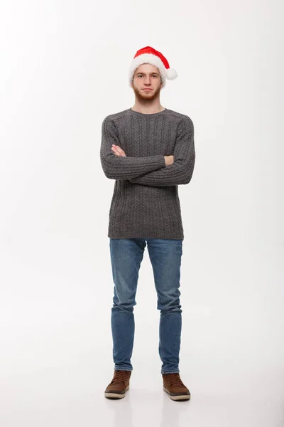 Holiday Concept - Junger Mann mit Bart im Pullover mit verschränkten Armen posiert auf weißem Hintergrund. — Stockfoto