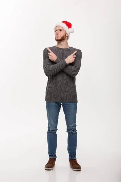 홀리데이 컨셉트 - 스웨터를 입은 젊은 턱수염 사람 이 위로 놀고 손가락을 가리키는 것을 즐긴다. — 스톡 사진