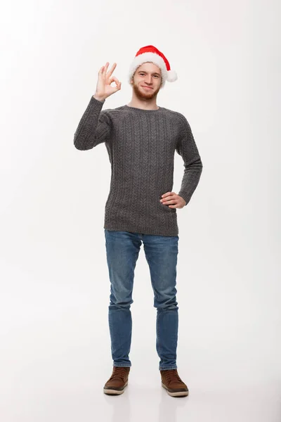 Holiday Concept - молодий бородатий чоловік в светрі дає знак ок для камери . — стокове фото