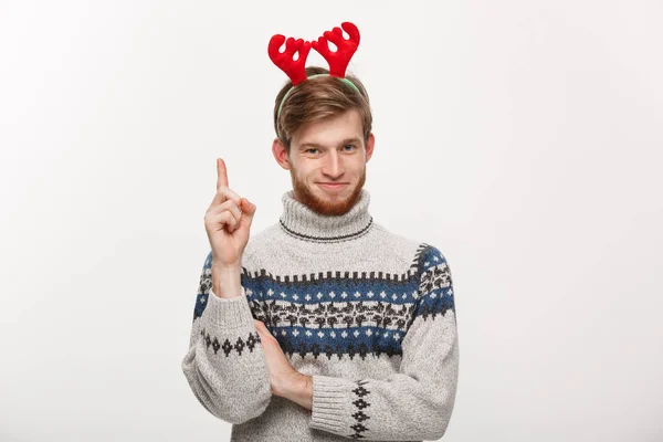 Holiday Concept - Jonge baard man in trui genieten van spelen en wijzen vinger naar boven. — Stockfoto