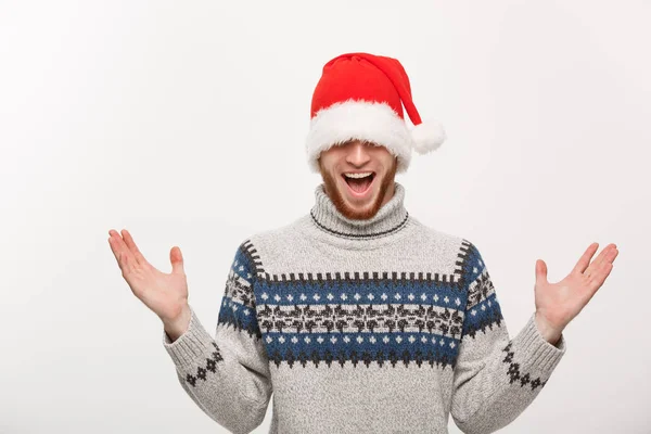 Holiday Concept - Νεαρός γενειοφόρος με πουλόβερ απολαμβάνει να παίζει με το καπέλο santa. — Φωτογραφία Αρχείου